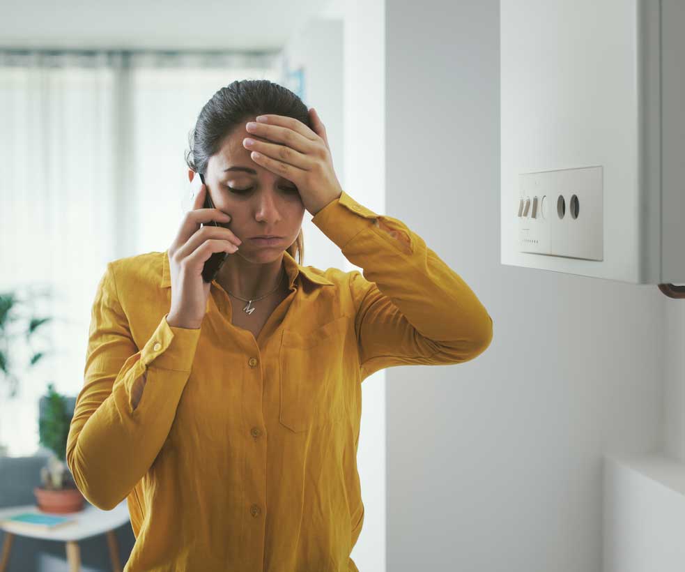 Stressed woman next to a broken boiler