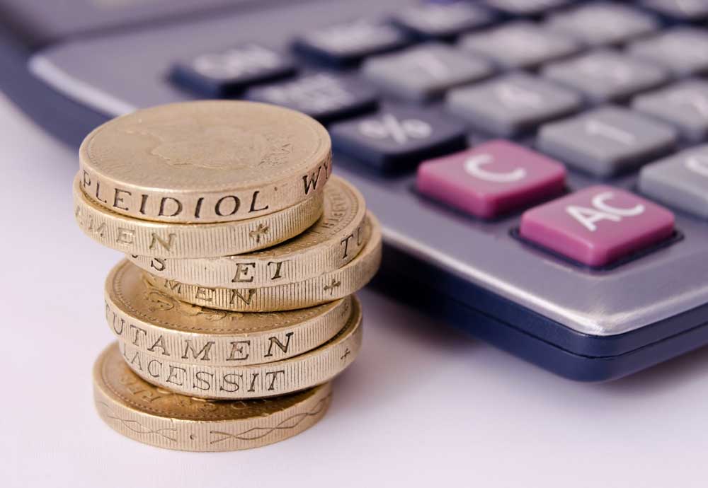 A pile of coins next to a calculator
