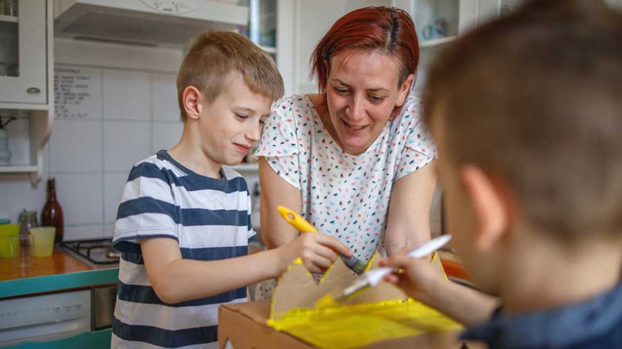 Children painting with their mother in the kitchen