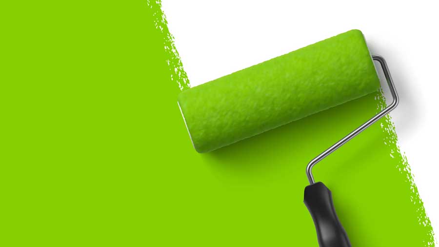 Paint roller painting a wall green