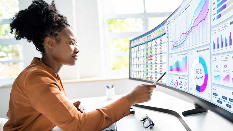 A woman analyses data on multiple computer screens