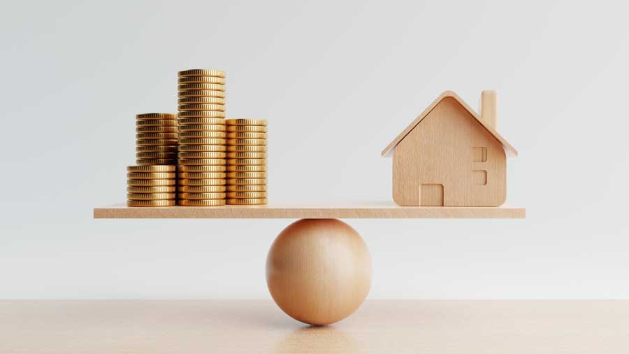 Wooden house and a pile of gold coins balance on a scale