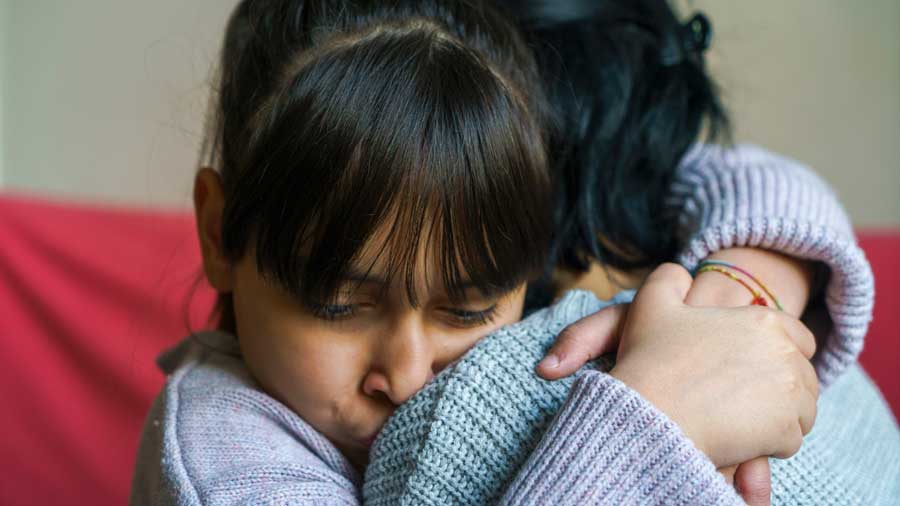 Upset young girl hugs her mother tightly