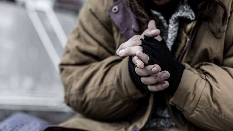Homeless man rubs his hands together for warmth