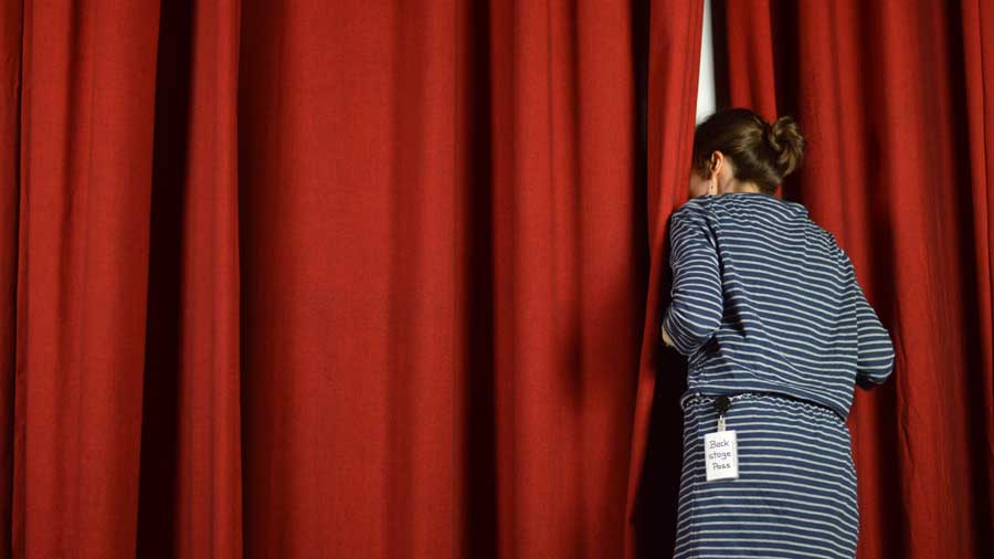 A woman peeks behind the curtains backstage