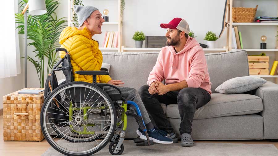 A young man in a wheelchair chats to a friend