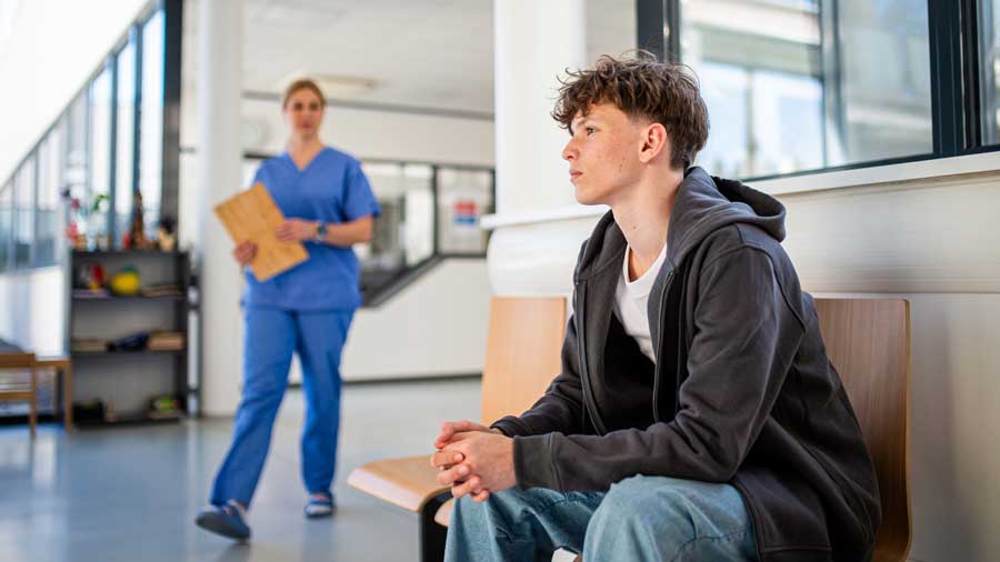 A young man sits in a hospital waiting area