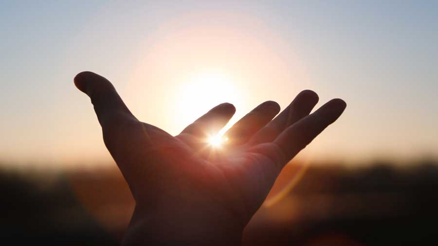 A hand stretched out towards the rising sun