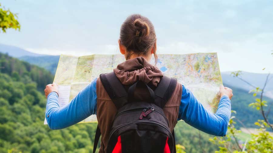 A hiker plots her route on a map
