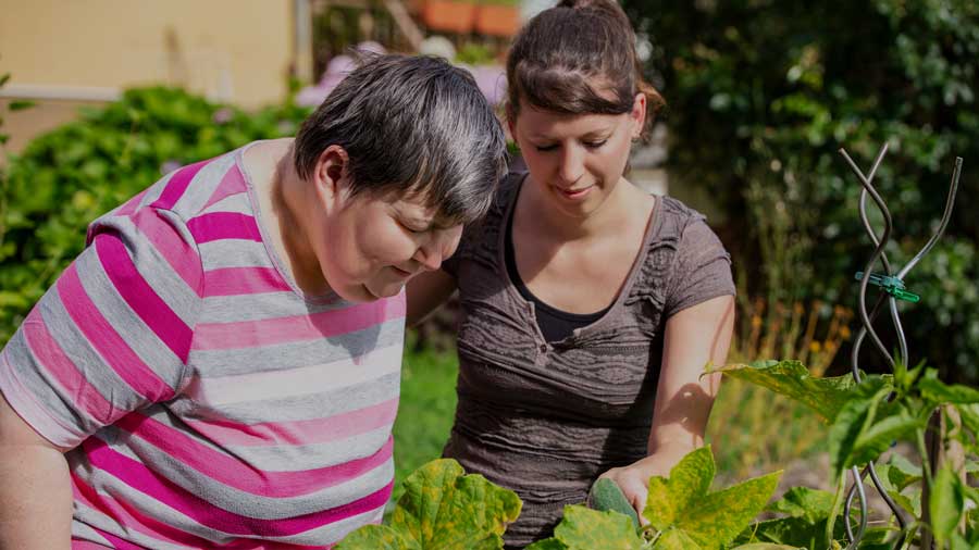 A disabled woman and her carer in the garden