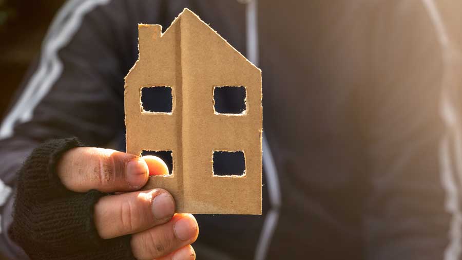 A hand holds a cardboard cutout of a house