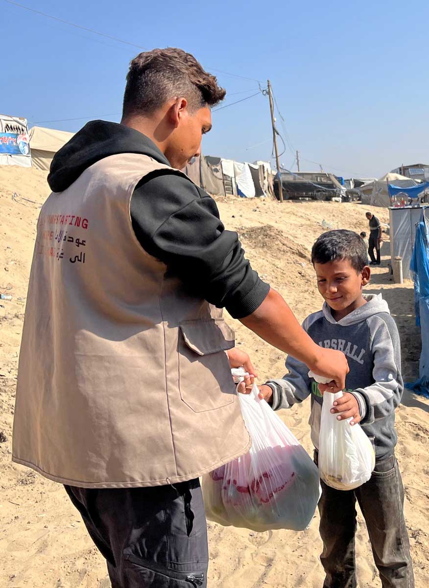 A Gazan boy is given bags of fresh fruit and vegetables