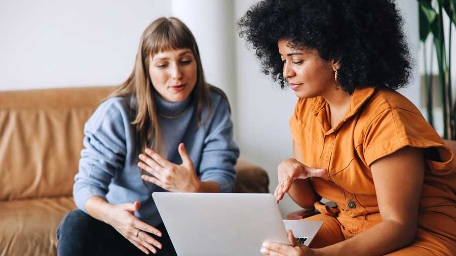 Two women discuss information on a laptop