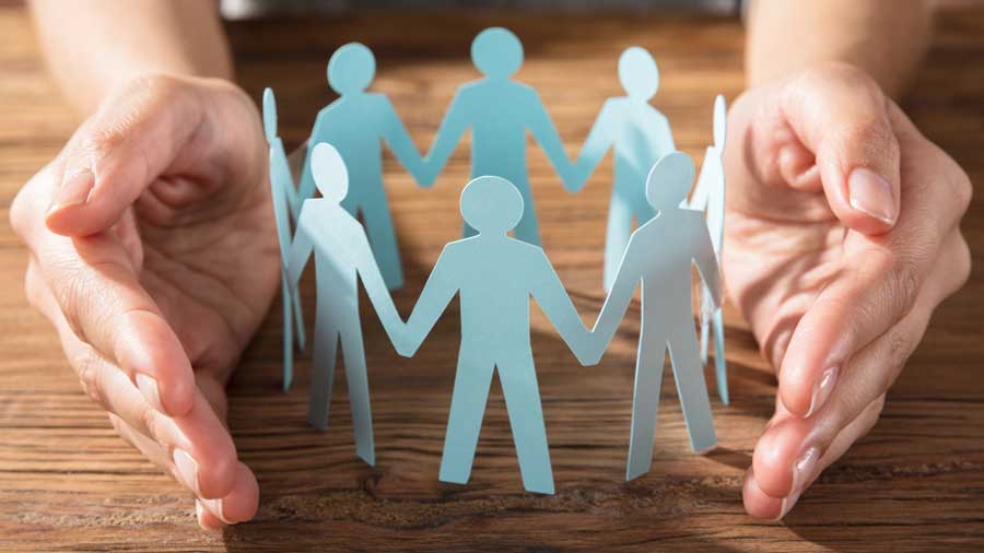 Hands protecting paper cutout figures