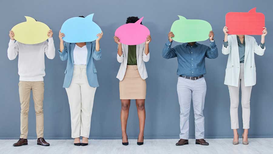 A mixed group of people holding up colourful speech bubbles