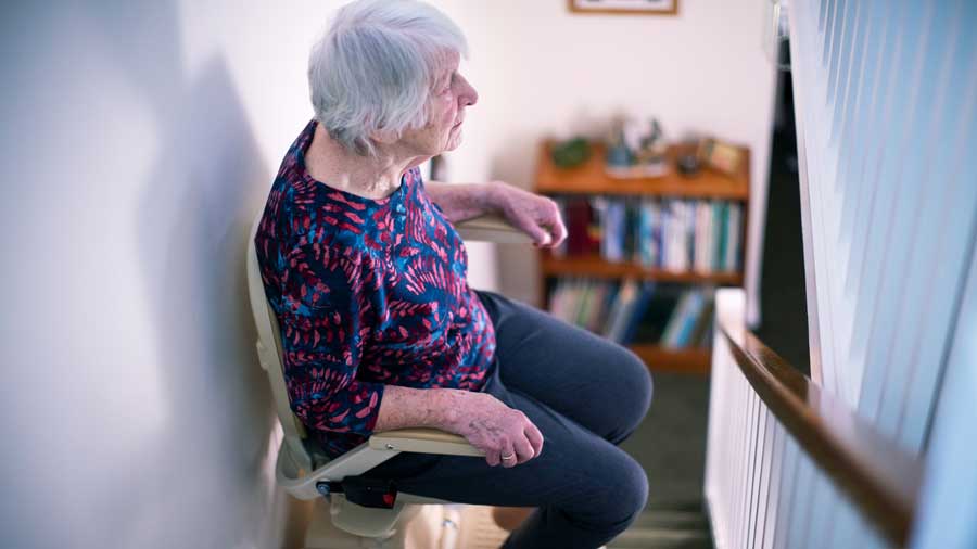 Older woman sitting on a stair lift at home