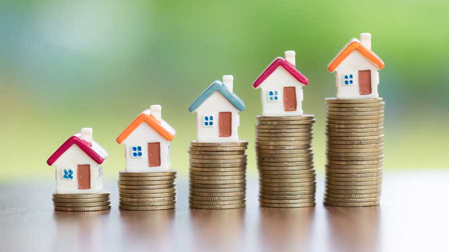 Model houses sitting on piles of coins