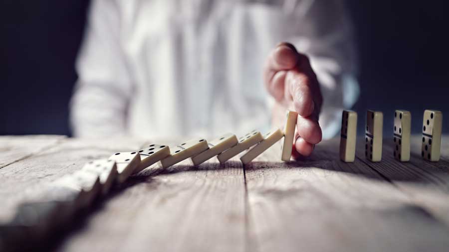 A hand stops dominos from falling