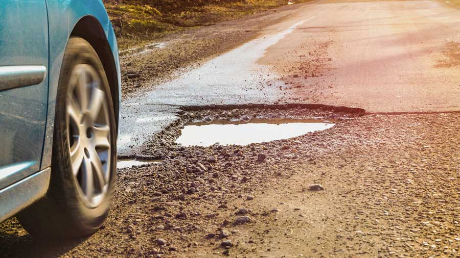 A car wheel about to drive over a pothole in the road