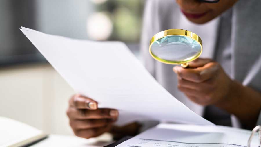 A woman closely examines a document with a magnifying glass