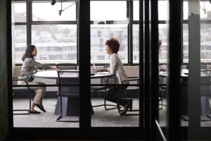 Two Millennial Businesswomen Meeting For A Job Interview, Full Length, Seen Through Glass Wall interviewing