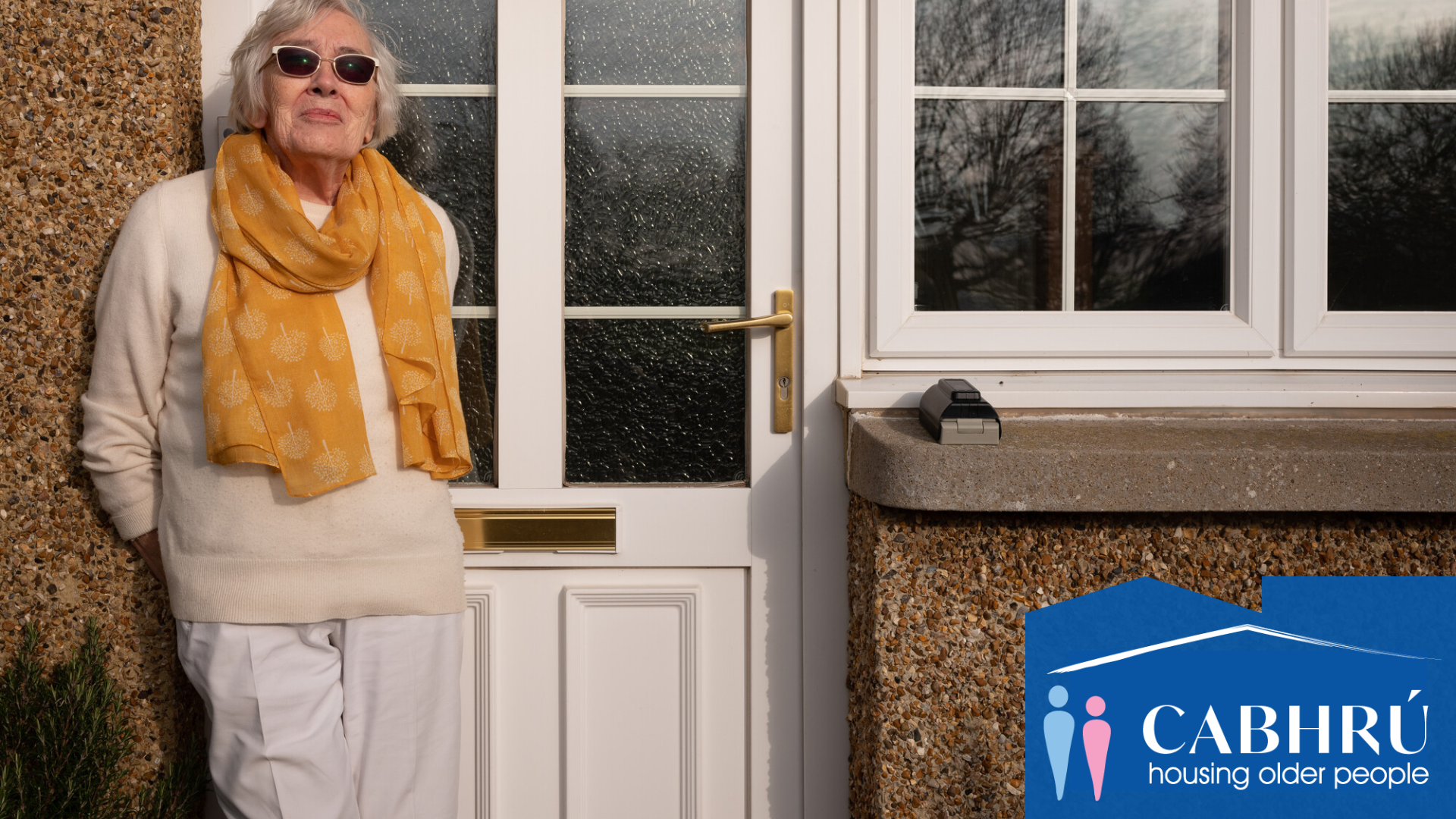 Cabhru case study - older woman standing outside a house with sun glasses on. Image from Centre for Ageing Better Library.