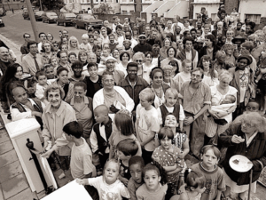 A large crowd of children and adults pose for a photo while the Chair of WECH cuts the ribbon on the front gate.